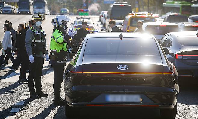 “교통법규 위반하셨습니다” 서울경찰청이 끼어들기·꼬리물기 위반에 대한 대대적인 단속에 나선 7일 경찰이 서대문구 연세대 교차로에서 차량 한 대를 세우고 단속과 계도를 진행하고 있다. 승용차 기준 꼬리물기는 범칙금 4만원, 끼어들기는 범칙금 3만원과 벌점 10점이 부과된다. 뉴시스
