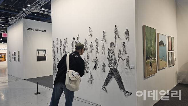 ‘2025 화랑미술제’ 전경. 신진작가 발굴 프로그램인 ‘줌인 특별전’에 선정된 신진작가 10명의 작품을 전시한 섹션에서 한 관람객이 작품들을 유심히 살펴보고 있다(사진=오현주 문화전문기자).