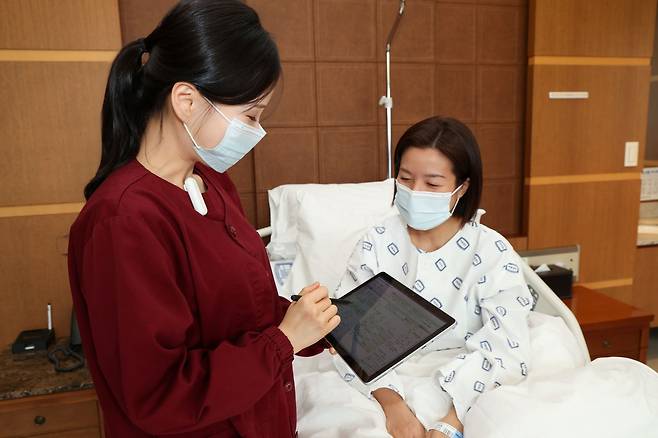 서울성모병원 간호사가 태블릿을 활용해 환자와 모바일 간호정보를 확인하고 있다.[서울성모병원 제공]