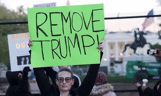 같은 날 “트럼프를 제거하라”고 적힌 플래카드를 든 시위 참여자 모습. 워싱턴=AP·로이터연합뉴스