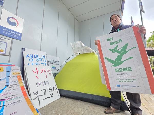 박중록 낙동강하구지키기전국시민행동 공동집행위원장이 9일 오전 창원시 성산구 신월동 낙동강유역환경청 정문 앞쪽에 설치한 텐트 앞에서 손팻말을 들고 있다. 그는 지난달 26일 낙동강청 정문 앞에 3~4인용 텐트를 쳤다. 이날부터 15일 째 집에 가지 않고 천막생활을 하고 있다. /최석환 기자