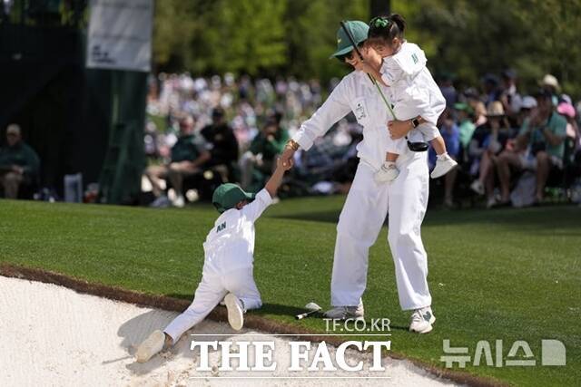 지난해 마스터스 전통 행사 중 하나인 파3콘테스트에 참여한 안병훈의 가족들. 부인 최희재씨가 딸 지우를 안은 채 아들 선우가 벙커에서 나올 수 있도록 도와 주고 있다./AP.뉴시스