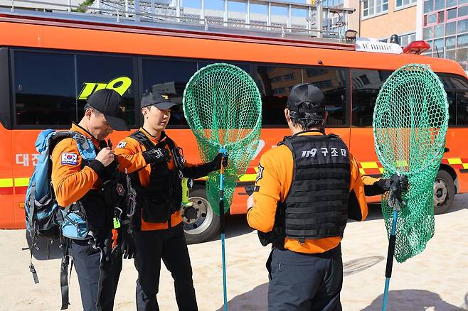 지난 8일 대전 중구 사정동 오월드에서 늑대 1마리가 탈출해 인근 초등학교에서 목격 신고가 접수된 가운데, 이날 오후 이 학교 교내에서 소방 대원들이 포획망을 들고 출동을 준비하고 있다. 연합뉴스