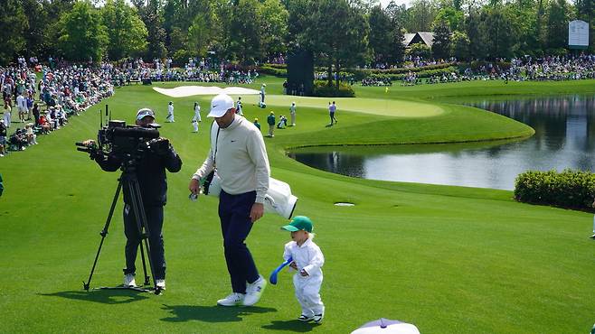 스코티 셰플러의 장남 베넷(오른쪽)이 8일(현지 시간) 미국 조지아주 오거스타 내셔널GC 옆 코스에서 열린 마스터스 파3 콘테스트 중 플라스틱 채를 팔에 끼고 바쁘게 다음 홀 티잉 구역으로 이동하고 있다. 오거스타=양준호 기자