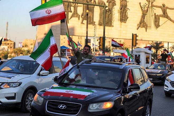 미국과 이란이 전격적인 잠정 휴전에 합의한 다음날인 2026년 4월8일 이웃나라인 이라크의 수도 바그다드 중심가 타흐리르 광장에서 주민들이 이란 국기를 흔들며 축하하고 있다. AFP 연합뉴스
