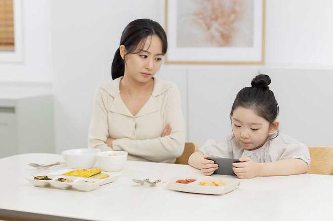 스마트폰을 보면서 식사하는 아이들은 올바른 식습관 형성과 균형 잡힌 영양 섭취가 어려울 수 있다. /클립아트코리아