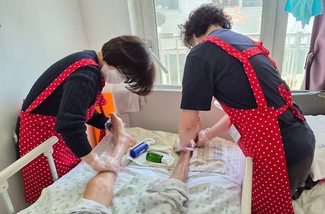 주님의교회 호스피스부 봉사자들이 지난해 경기 용인 한 호스피스 병동에서 환자의 발을 씻긴 뒤 로션으로 마사지하며 돌봄을 이어가고 있다. 주님의교회 제공