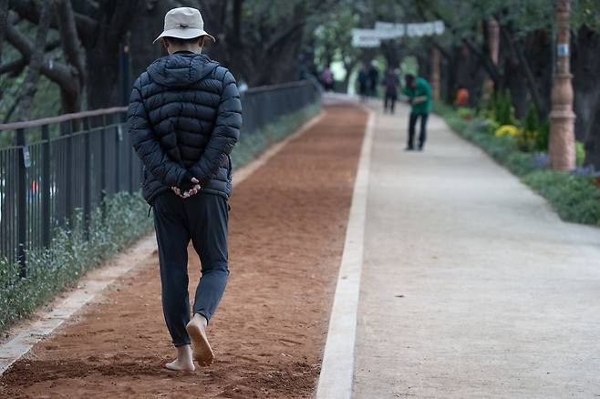 집 안에서만 지내면 몸을 덜 움직이고 근육이 사라져 더 잘 넘어진다. 한 시민이 황톳길 걷기 행사에서 맨발로 걷고 있다. 사진 연합뉴스
