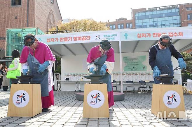 [서울=뉴시스]  이경상 주교, 정순택 대주교, 박용만 이사장(왼쪽부터)이 4월 12일 명동대성당에서 열린 ‘철조망 십자가 프로젝트’ 개막식에서 철조망을 두드려 펴는 시연을 하고 있다. (사진=천주교 서울대교구 제공) 2026.04.13. photo@newsis.com