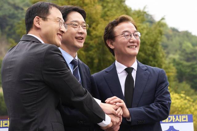 14일 봉하마을에서 열린 부울경 메가시티 출정식에서 김상욱, 김경수, 전재수 후보(왼쪽부터)가 손을 맞잡고 있다. 더불어민주당 제공