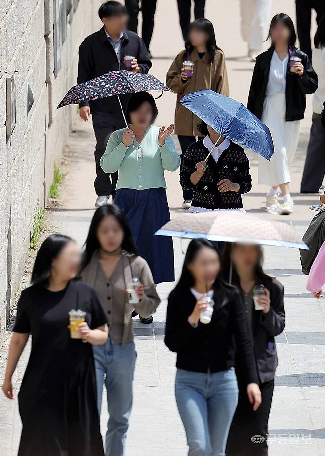 서울 낮 최고기온이 28도까지 오르며 초여름 날씨를 보인 14일 서울 중구 청계천에서 시민들이 양산을 쓰고 이동하고 있다. 뉴시스