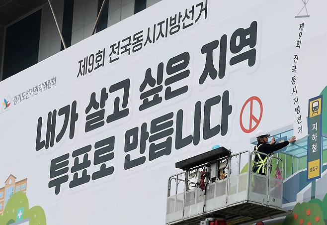 제9회 전국동시지방선거를 앞둔 9일 경기도 수원시 영통구 경기도선거관리위원회 청사 외벽에 관계자들이 투표참여를 독려하는 대형 현수막을 설치하고 있다. /뉴스1