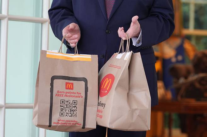 [워싱턴=AP/뉴시스] 도널드 트럼프 미국 대통령이 13일(현지 시간) 백악관에서 배달앱 '도어대시'의 샤론 시먼스로부터 전달 받은 맥도날드를 들고 있다. 2026.04.14.