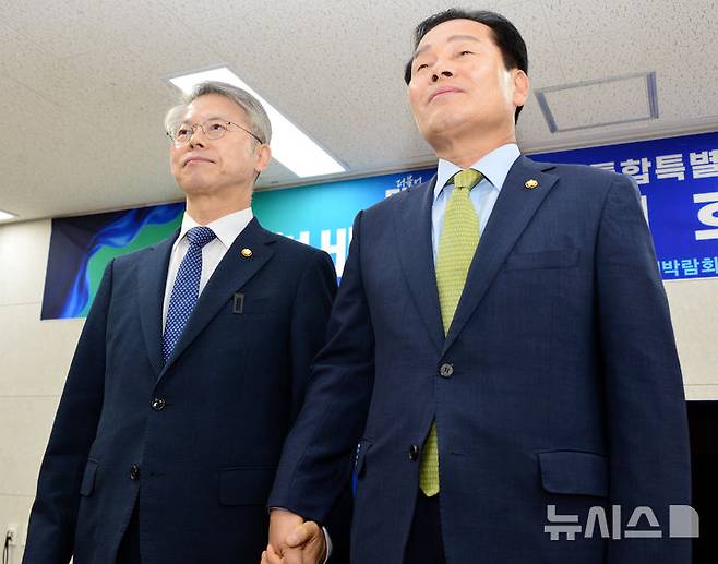 [여수=뉴시스] 김석훈 기자 = 더불어민주당 전남광주통합특별시장 본경선 주자인 민형배·주철현 예비후보가 1일 오전 여수세계박람회장 컨벤션센터에서 후보 단일화 공동선언문을 낭독한 뒤 손을 잡고 있다. 2026.04.01. kim@newsis.com