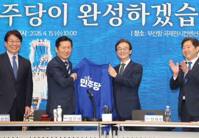 더불어민주당 정청래 대표가 15일 오전 부산 동구 부산항국제전시컨벤션센터에서 열린 현장 최고위원회에서 전재수 부산시장 후보에게 파란 점퍼를 입혀주기 전 들어 보이고 있다. 이재찬 기자 chan@