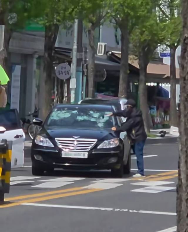 15일 울산 중구 한 도로에서 아내가 탄 차량 앞 유리를 고무망치로 파손시킨 50대 A씨가 경찰의 조사를 받고 있다. SNS 갈무리