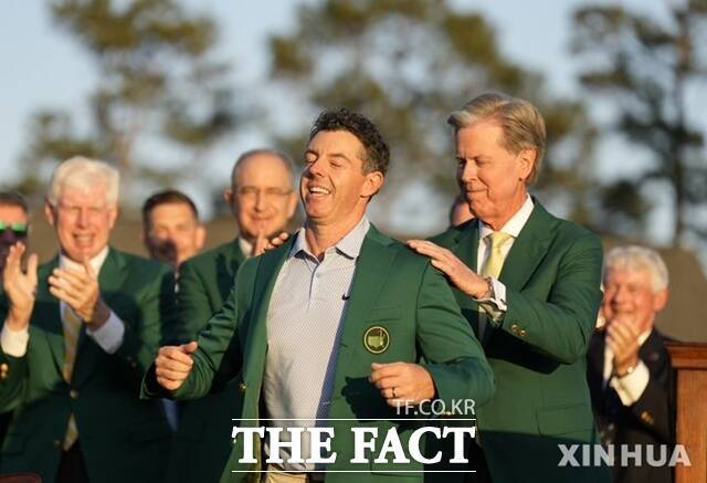 로리 맥길로이(왼쪽)가 오거스타내셔널의 프레드 리들리 회장의 도움으로 마스터스 우승의 상징인 그린 재킷을 입고 있다. 전년도 챔피언이 그린 재킷을 입혀주는 것이 관례이나 맥길로이가 2연패를 달성해 골프장 회장이 대신했다./AP.뉴시스