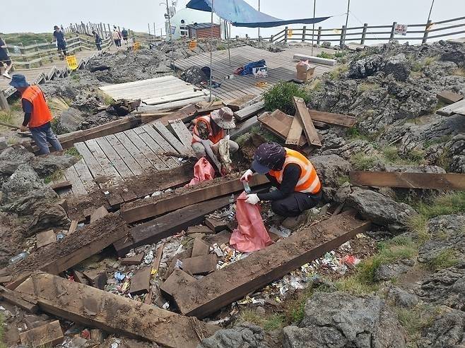 지난해 8월 한라산 동능 데크 철거 중 쓰레기 수거 작업. 연합뉴스(제주도 세계유산본부 제공)