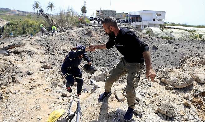 16일(현지시간)&nbsp;레바논 남부 티레 근처에서 주민들이 이스라엘 공습으로 부서진 카스미예 다리를 건너고 있다. EPA연합뉴스