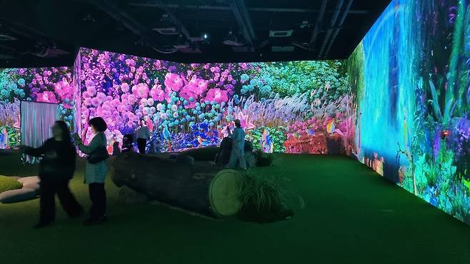 360도 생성형 AI로 구현된 ‘미지의 화원’ 전시 공간에서 관람객들이 몰입형 영상을 체험하고 있다.