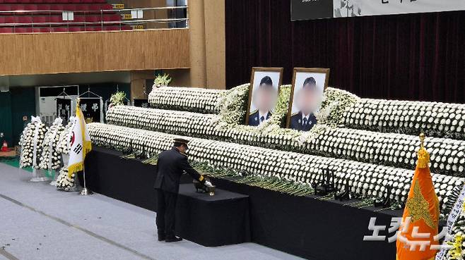 지난 14일 오전 두 순직 소방관의 영결식이 거행된 전남 완도군 농어민문화체육센터. 영결식이 끝난 후 동료 소방관이 두 순직 소방관의 영정사진 앞에서 향에 불을 붙이고 있다. 한아름 기자