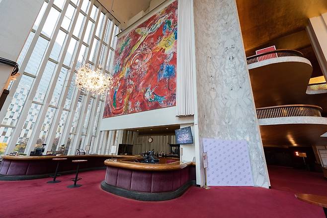 메트로폴리탄 오페라 하우스 로비에 설치된 마르크 샤갈의 대형 벽화 '음악의 승리'(The Triumph of Music). 붉은 바탕 위에 천사와 음악가, 새, 신화적 인물들이 역동적으로 뒤엉켜 샤갈 특유의 몽환적 화풍이 돋보인다. [메트로폴리탄 오페라 홈페이지 캡처]