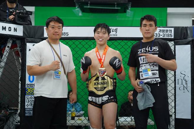1차 방어전에 성공한 KMMA 페더급 챔피언 임유홍(가운데)이 소속팀 경주쉴드MMA 지도자 이억열(왼쪽)과 함께 기념 사진을 찍고 있다. 사진제공 = 뽀빠이연합의원KMMA파이터에이전시