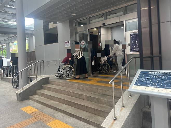 20일 오전 10시 '장애인의 날'을 맞아 찾은 전남대학교병원 본관 출입구. 휠체어를 이용한 환자들이 건물 안으로 들어가기 위해 계단 앞에서 발걸음을 멈추고, 보호자와 직원의 도움을 받아 힘겹게 이동하고 있다. /박건우 기자