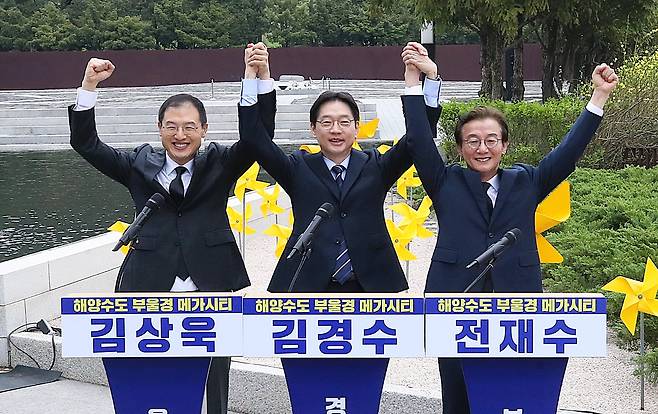 더불어민주당 부울경(부산·울산·경남) 시장·도지사 후보가 14일 오전 경남 김해시 진영읍 봉하마을에서 열린 '해양수도 부울경 메가시티 공동출정식'에서 손을 맞잡아 들어올리고 있다.    왼쪽부터 김상욱 울산시장 후보, 김경수 경남지사 후보, 전재수 부산시장 후보./20260414 김동환 기자