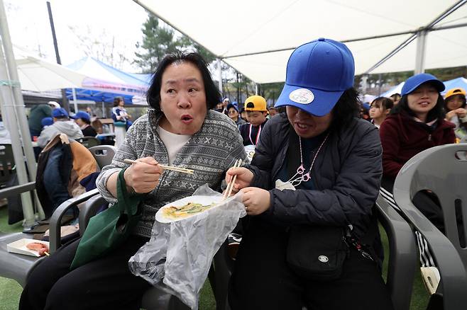 ‘2026년 세계다운증후군의 날 기념 장애인, 비장애인 함께 하는 걷기 행사’가 열린 지난 11일 서울 노원구 공릉동근린공원에서 허정미씨(왼쪽)가 정미라씨와 부침개를 나눠 먹고 있다. 김영원 기자 forever@hani.co.kr