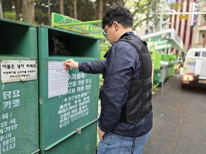 제주시 생활환경과 직원이 무단 설치된 의류수거함에 행정대집행을 예고하는 계고장을 붙이고 있다.