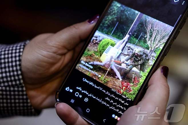 20일(현지시간) 레바논 베이루트에서 한 여성이 소셜미디어 게시물을 확인하고 있다. 게시물 속 사진에는 이스라엘군 병사가 십자가에서 떨어진 예수상의 머리를 슬레지해머로 내리치는 모습이 담겨 있다. 사진이 온라인을 통해 퍼져 나가며 논란이 커지자, 베냐민 네타냐후 이스라엘 총리는 해당 병사에 대해 엄중한 조치를 취하겠다고 밝혔다. 2026.04.20. ⓒ AFP=뉴스1