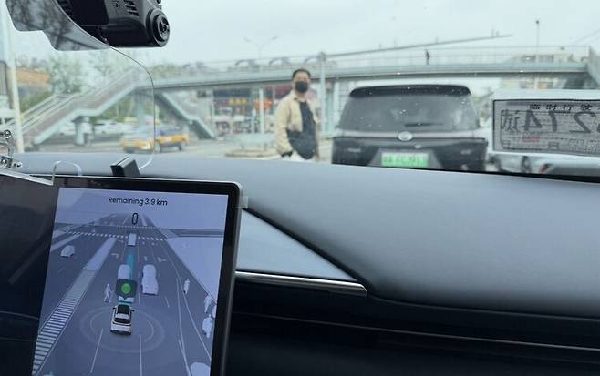 지난 17일 베이징의 한 도로에서 중국 자율주행 기술기업 포니에이아이(AI)의 무인택시가 무단횡단을 하는 보행자를 보고 멈춰 섰다. 베이징/이정연 특파원