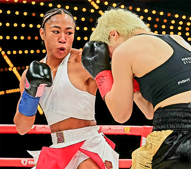 바움가드너가 매디슨 스퀘어 가든에서 국제복싱연맹 세계복싱협회 세계복싱기구 챔피언으로서 도전자 신보미레를 공격하고 있다. ‘알리시아’는 한국계, 국화 문장은 일본계 혈통을 뜻한다. 신보미레는 세계복싱평의회 인터내셔널 챔피언을 지냈다. 사진=Getty Images=연합뉴스 제공