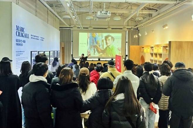 전북 전주시 팔복예술공장에서 열리고 있는 마르크 샤갈 특별전을 찾은 관람객들이 큐레이터의 설명을 듣고 있다. 전주문화재단 제공