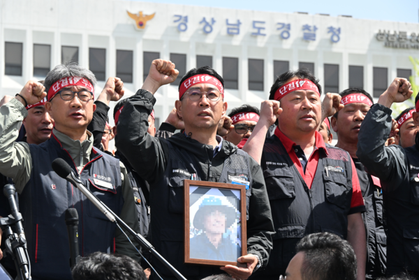 21일 화물연대 소속 노동자 등이 희생자 영정사진을 들고 경남경찰청 앞에서 진주 예하리 노동자 사망 관련 CU BGF로지스와 경찰을 규탄하는 화물연대 기자회견을 하고 있다.희생 노동자는 20일 오전 10시 32분께 진주시 정촌면 예하리 BGF로지스 진주센터 인근 민주노총 화물연대 경남지역본부 소속 CU편의점 화물운송 노동자 집회 현장에서 사망했다./김구연 기자