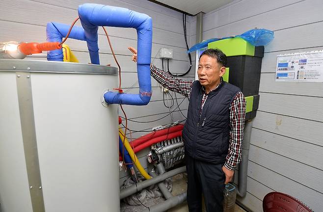 충북 괴산 장암리 주민 박재만씨가 집 뒤에 설치한 열교환기와 축열탱크를 보여주고 있다. 김성태 객원 기자