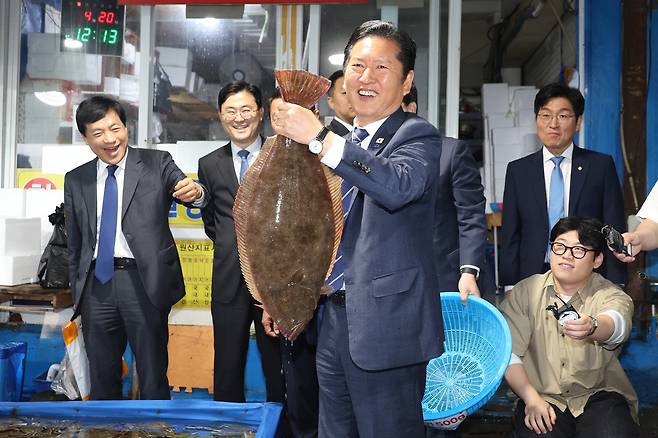 정청래 더불어민주당 대표가 지난 20일 충남 보령시 대천항수산시장을 방문해 광어를 들어보고 있다. 연합뉴스