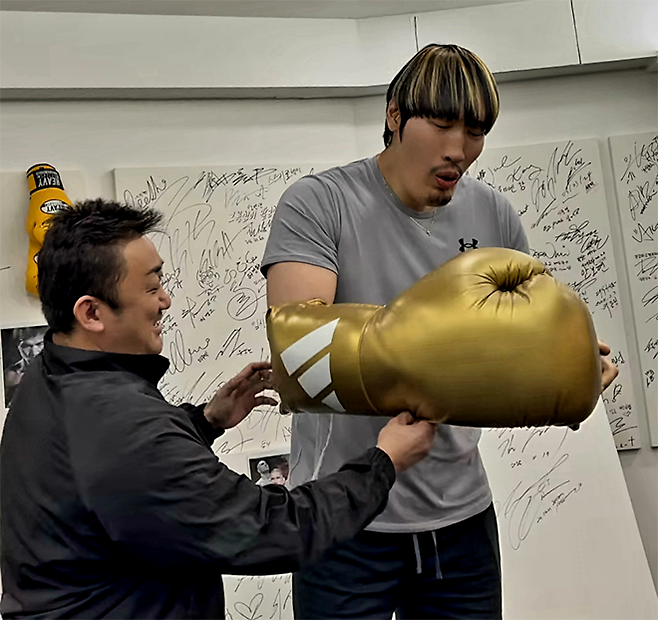 제41대 천하장사 최홍만이 2026년 4월 서울특별시 강남구 청담동 빅펀치복싱클럽에서 훈련을 마친 후 영화배우 Don ‘마동석’ Lee가 선물한 대형 글러브를 껴보고 있다. 사진=올파이츠유니버스/@donlee