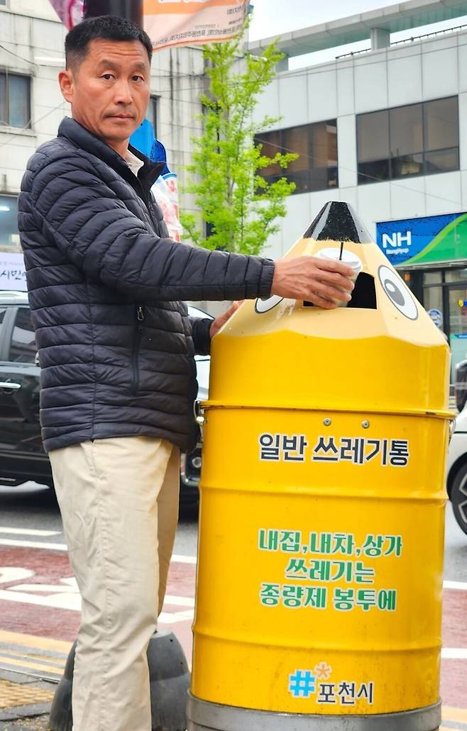 ▲ 포천시청 환경공무직 차진석 씨가 직접 고안한 '몽당연필 휴지통' 투입구에 테이크아웃 컵을 투입하고 있다. 차 씨는 현장 데이터를 기반으로 종량제 봉투 진입은 막고 소형 폐기물만 수거할 수 있는 '18cm 설계'를 적용했다. /이광덕 기자 kdlee@incheonilbo.com