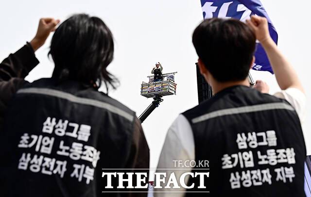 23일 오후 경기 삼성전자 평택캠퍼스 앞에서 열린 '4.23 투쟁 결의대회'에 참석한 초기업노조 삼성전자 지부 조합원들이 크레인 위에서 발언하는 최승호 삼성전자 지부 위원장을 바라보고 있다. /평택=임영무 기자