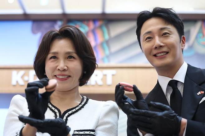 김혜경 여사가 23일(현지 시간) 베트남 하노이 서호 롯데몰에서 열린 K-문화관광대전에서 배우 정일우와 마카롱을 들어보이고 있다. 뉴시스