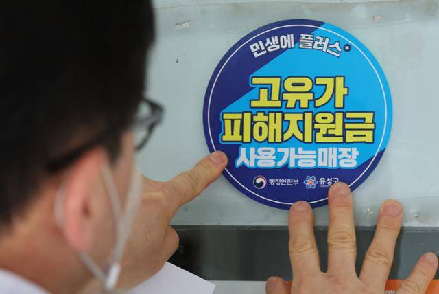 고유가 피해지원금 신청을 앞두고 23일 대전 유성구 한 식당 주인이 피해지원금 사용가능매장 안내문을 붙이고 있다. 뉴스1