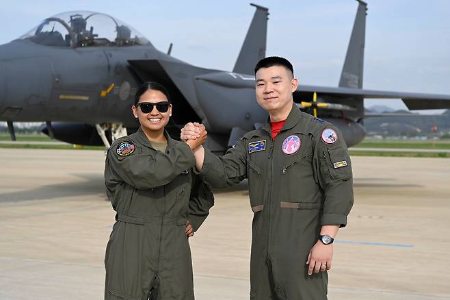 F-15K 전투기를 배경으로 손을 맞잡고 있는 한미 전투 조종사. 사진 공군