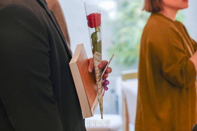 책을 구매한 손님이 책과 함께 장미꽃을 들고 있다.