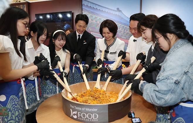 이재명 대통령과 베트남을 방문 중인 김혜경 여사가 23일 하노이 서호 롯데몰에서 열린 K문화관광대전에서 배우 정일우 등 참석자들과 비빔밥을 만들고 있다. /뉴스1