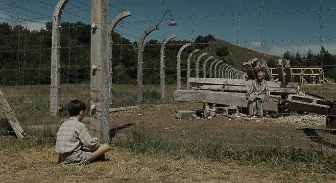 영화 <줄무늬 파자마를 입은 소년>의 두 소년이 철조망을 사이에 두고 서로를 바라보고 있다. 팝엔터테인먼트 제공