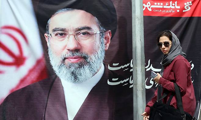 이란 테헤란의 거리에서 한 여성이 이란 최고지도자 모즈타바 하메네이의 사진 앞을 지나가고 있다. EPA연합뉴스