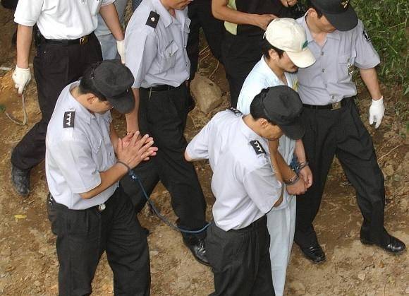 연쇄살인범 유영철이 2004년 8월 수사당국의 현장 검증 과정에서 경찰의 호송을 받으며 이동하고 있다. 서울신문 DB