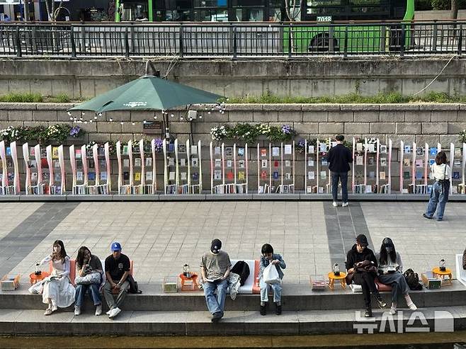 [서울=뉴시스]김세은 인턴기자 = 23일 서울 청계천에 마련된 독서 공간 '책읽는 맑은 냇가'에서 시민들이 책을 읽고 있다. 2026.04.23.